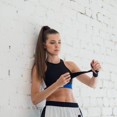 Young woman wrapping hands with black boxing wraps in gym practice boxing indoor working out fitness